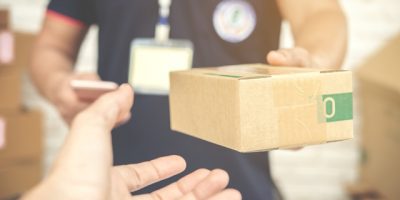delivery man smiling and holding a cardboard box